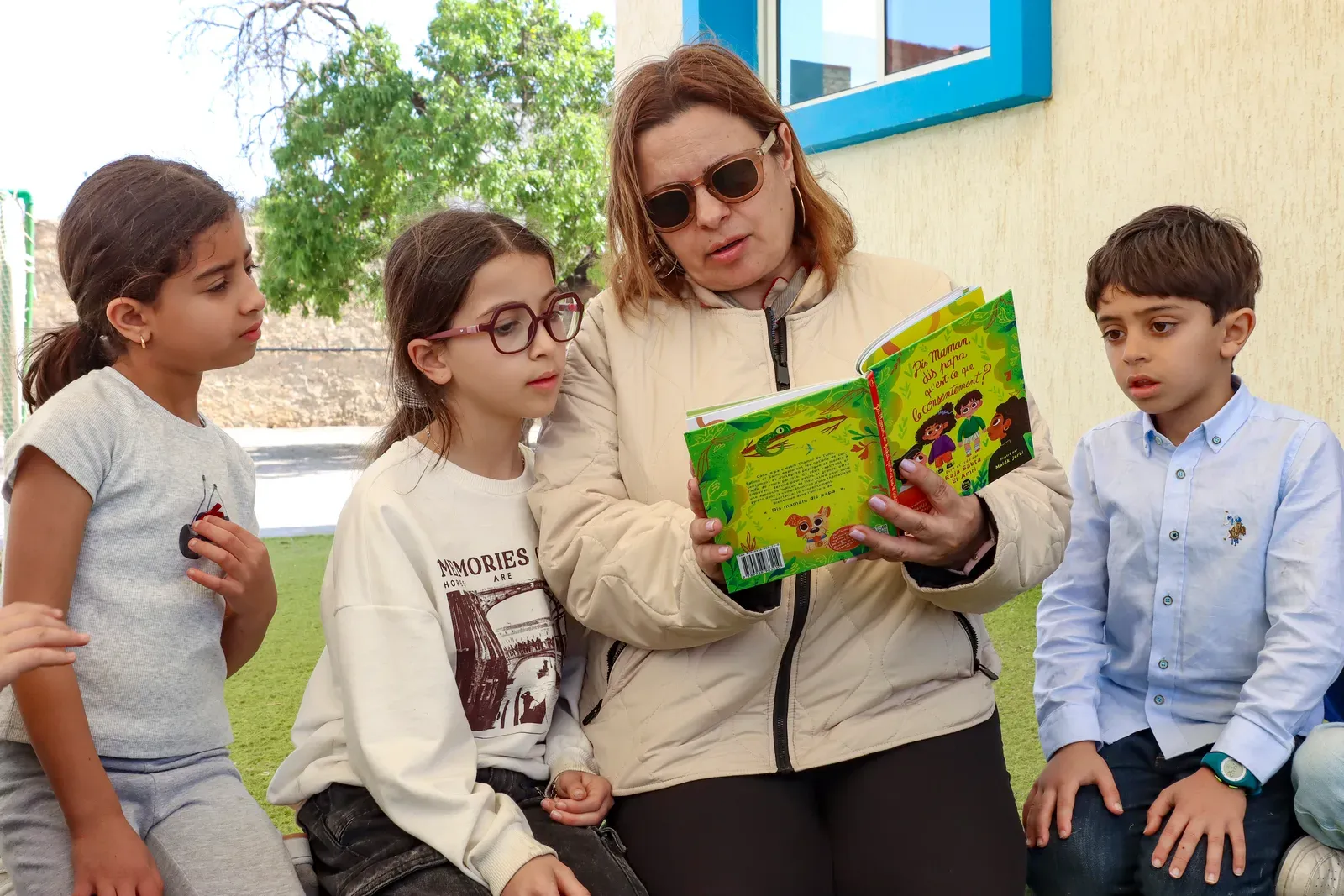 Une lecture à voix haute devant un groupe d’enfants, en extérieur